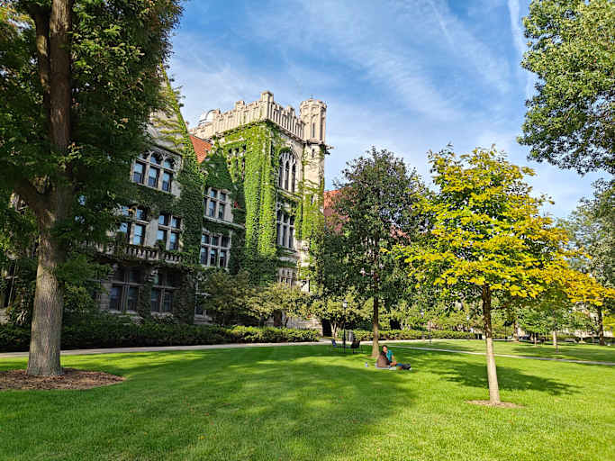 A pair of student sitting on the quadrangle lawn outside the residence halls on the University of Chicago campus.