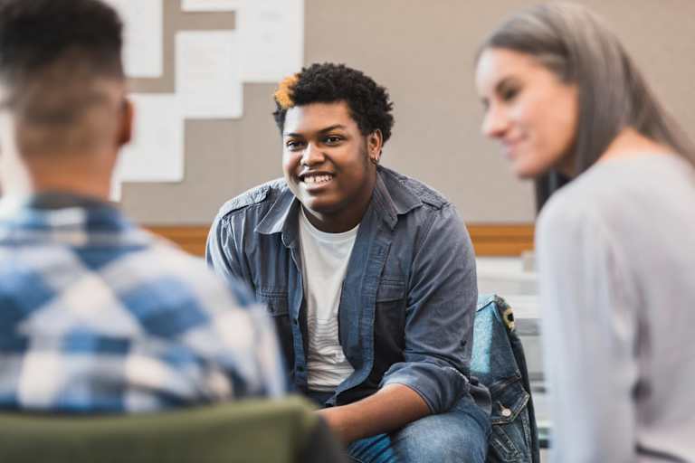 A young person meets with a therapist and another student to receive mental health care.