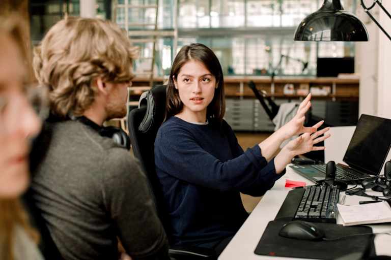 Two people talking while sitting at computers