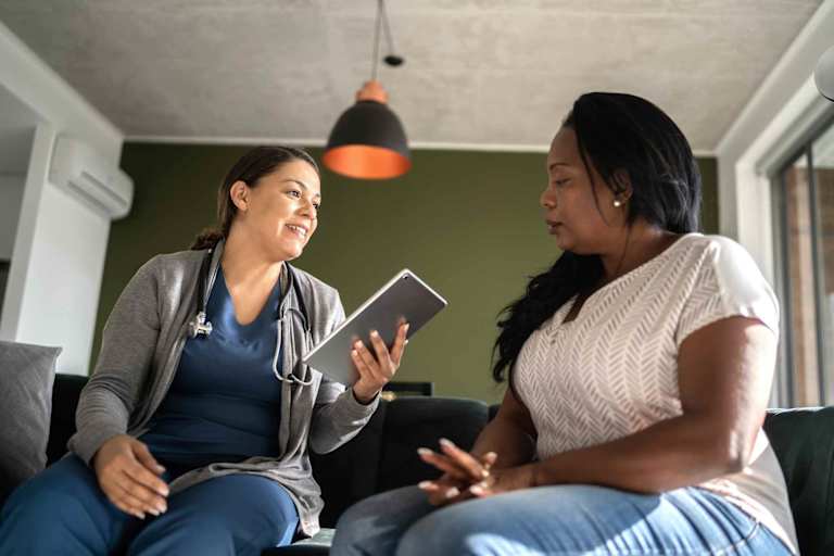 Nurse speaking to woman in her home