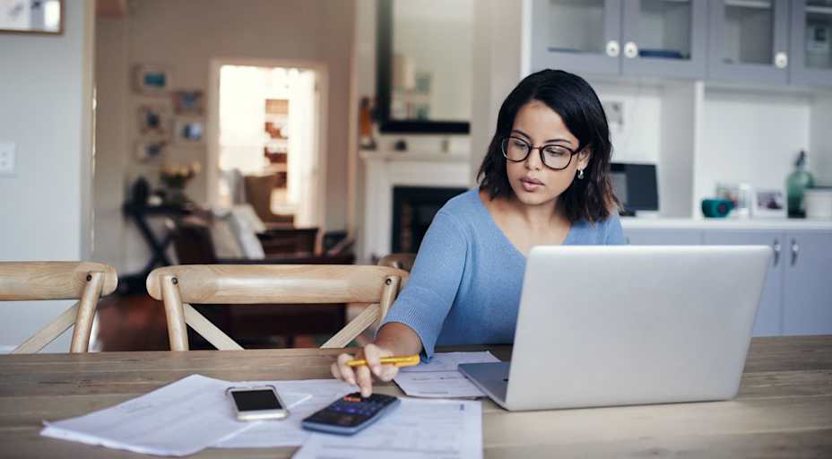 Woman working on laptop and calculator at home