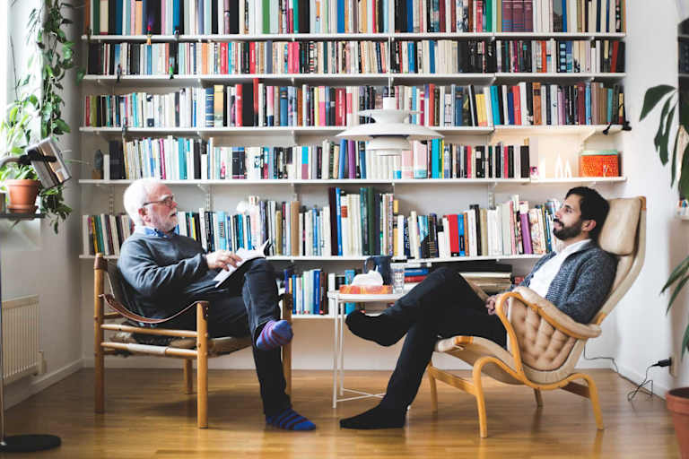 Psychologist speaking to client beside bookshelf