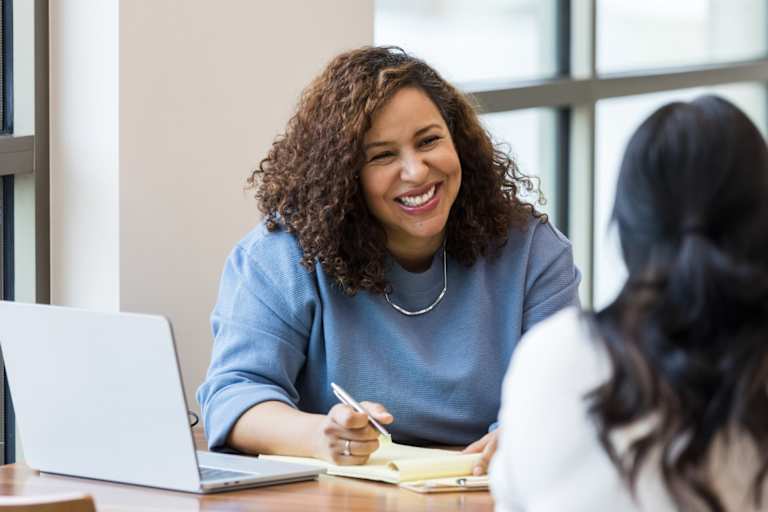 Mature businesswoman smiles encouragingly at unrecognizable coworker