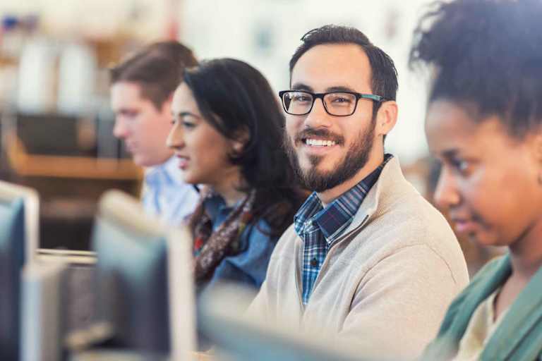 Happy man using computer in college computer class