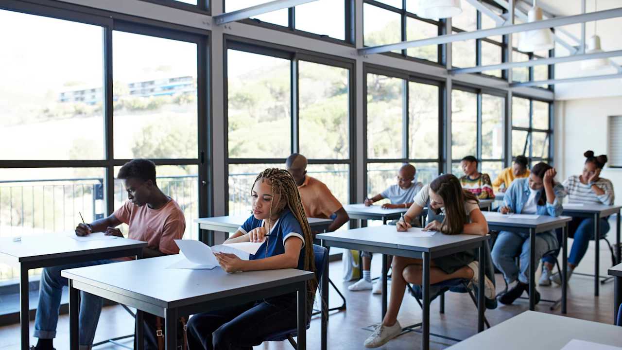 Young male and female students writing exam in classroom at community college