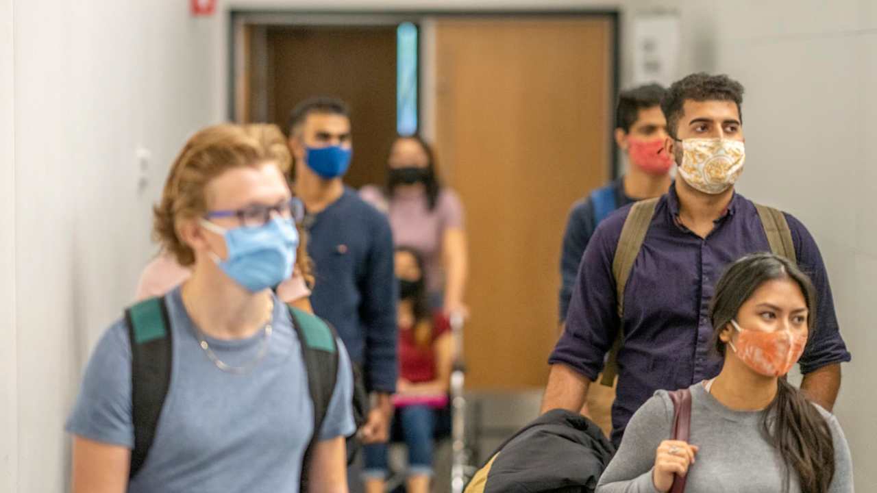 Colleges students filing into class while wearing protective face masks.