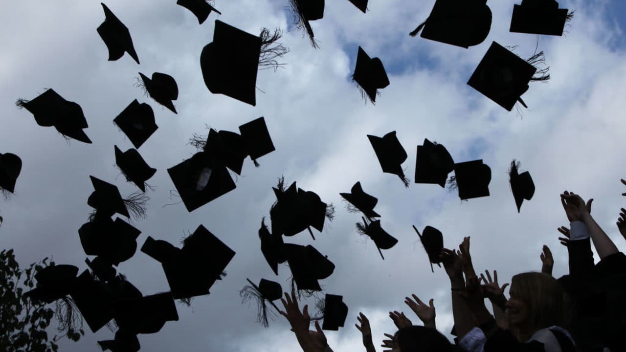 Students throw their graduation hats in the air during their graduation ceremony.