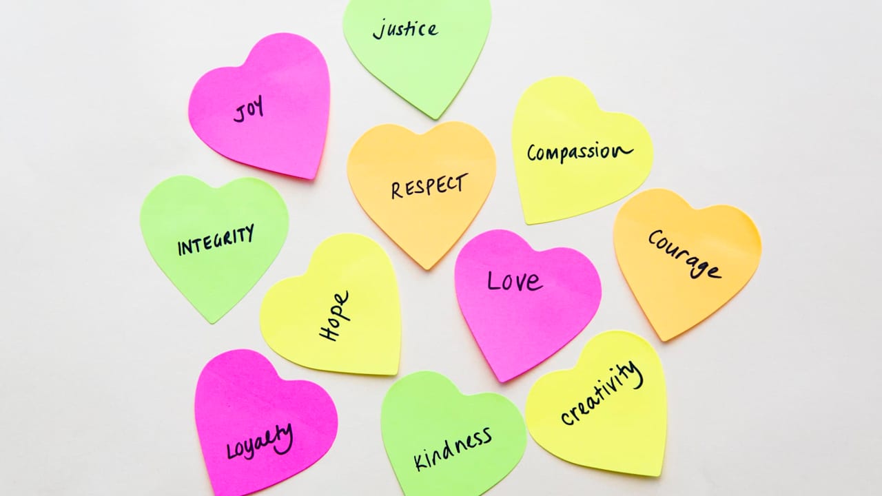 Values such as courage, justice, and creativity handwritten on heart shaped sticky notes.