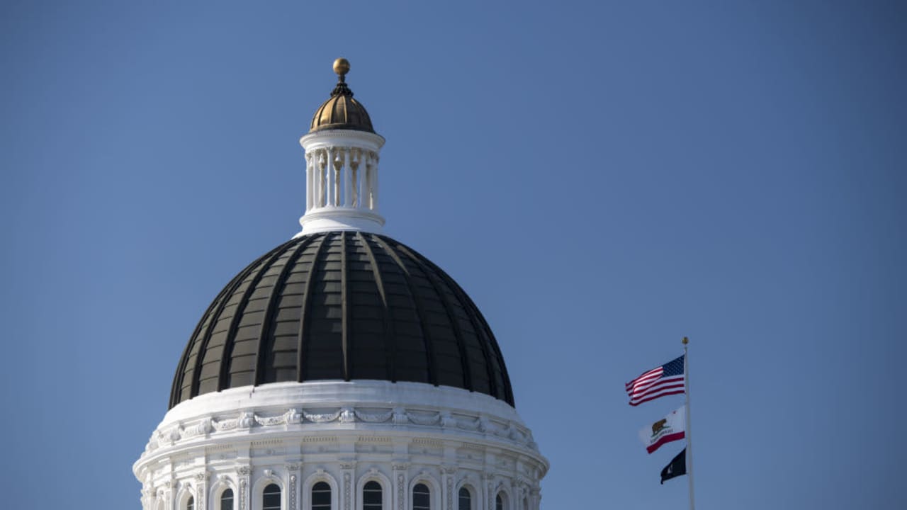 The American, California State, and POW/MIA flags fly next to the California State Capitol building in Sacramento, California