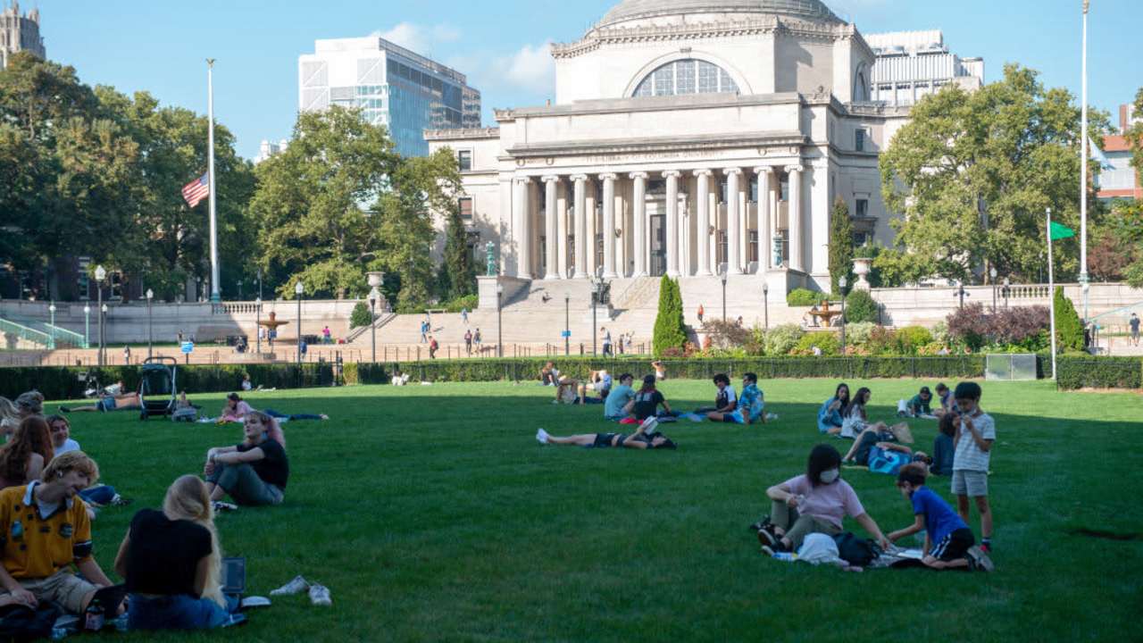 People sit on the grass at Columbia University in New York City. The university said it needs more time to reevaluate its data after a professor alleged it may have skewed numbers in previous years.