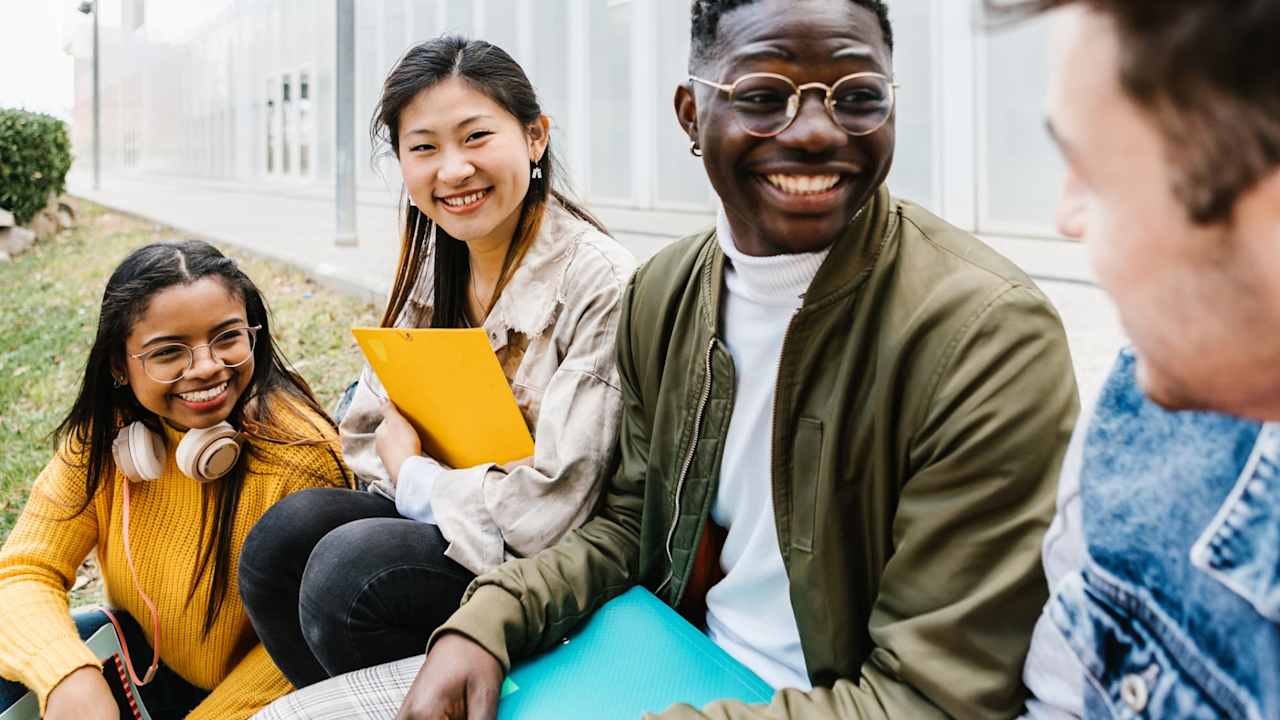 Multiethnic group of young student friends hanging out at university campus - Asian teenage girl is smiling at camera - International erasmus exchange concept