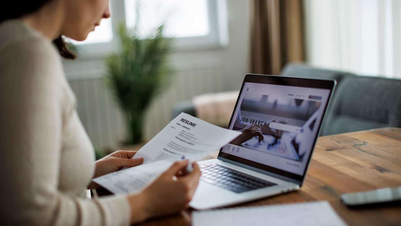 Woman reviewing her resume while searching for jobs online on her laptop