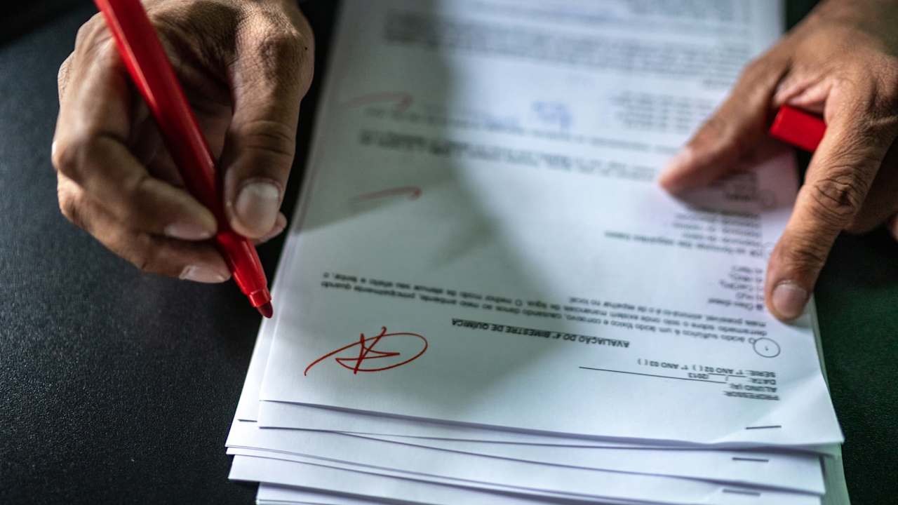 Instructor grading an assignment with a red pen