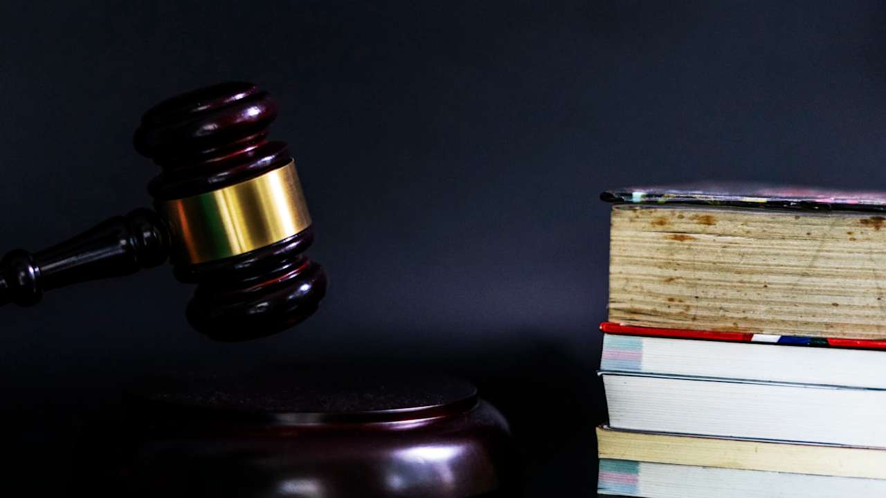 Law and Education concept. A picture of a gavel and a stack of books against a blank black background.