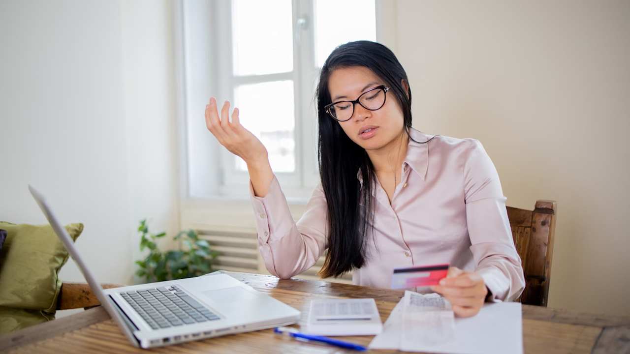 Woman looking frustrated while using a credit card