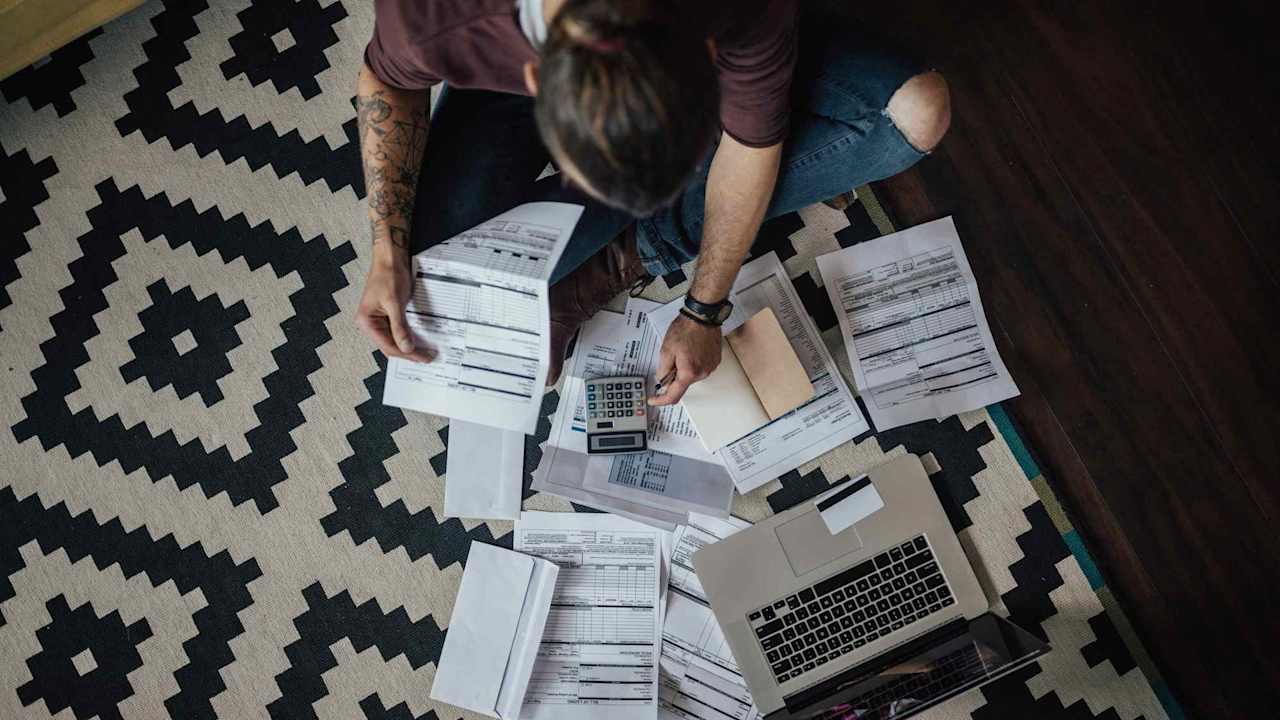 Student surrounded by papers, a calculator, and a laptop