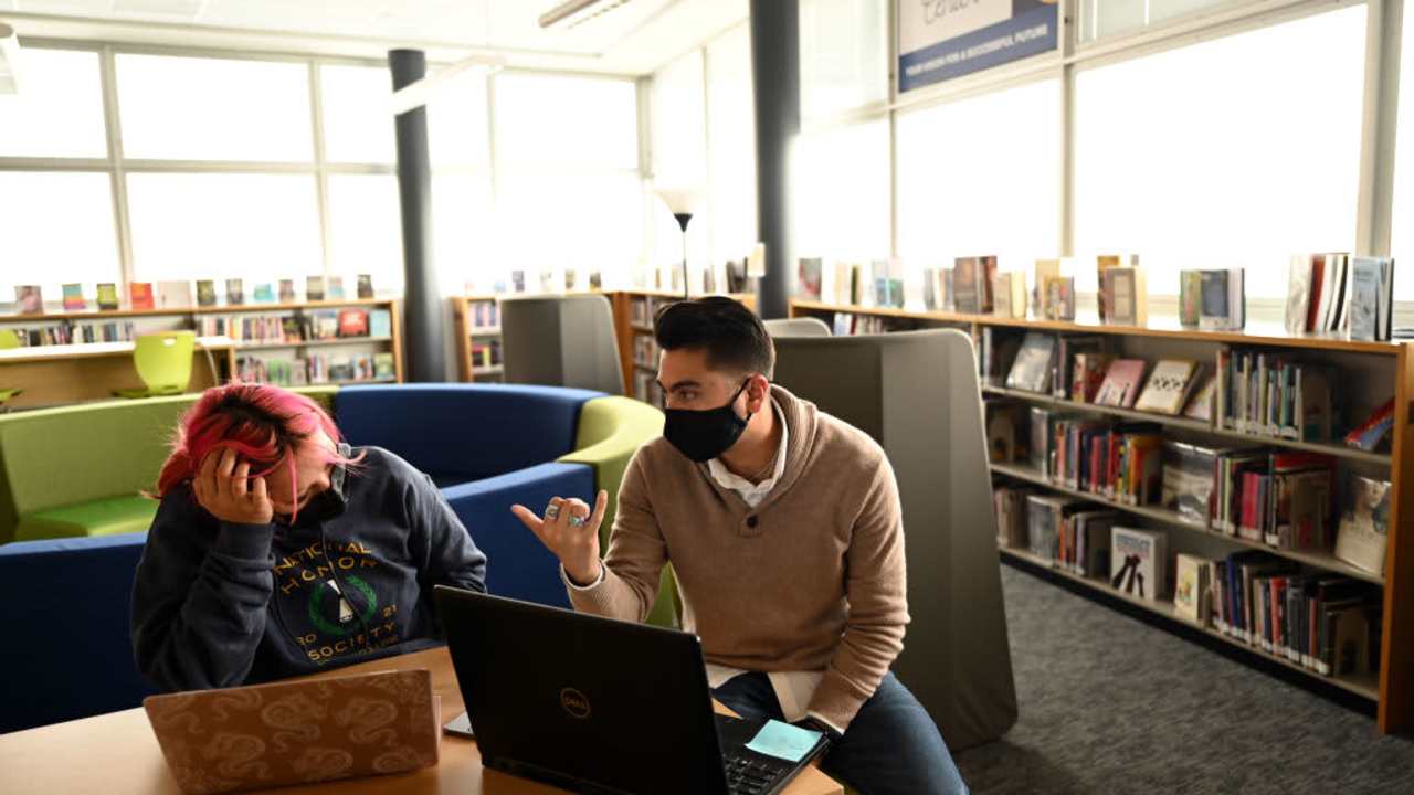 DENVER, CO - DECEMBER 9 : Derrek Sandoval, 32, right, helps Rosselyn Gurrola-Solis, 17, left, to apply scholarships at the library of Fred N. Thomas Career Education Center Early College in Denver, Colorado on Thursday, December 9, 2021.(Photo by Hyoung Chang/MediaNews Group/The Denver Post via Getty Images)