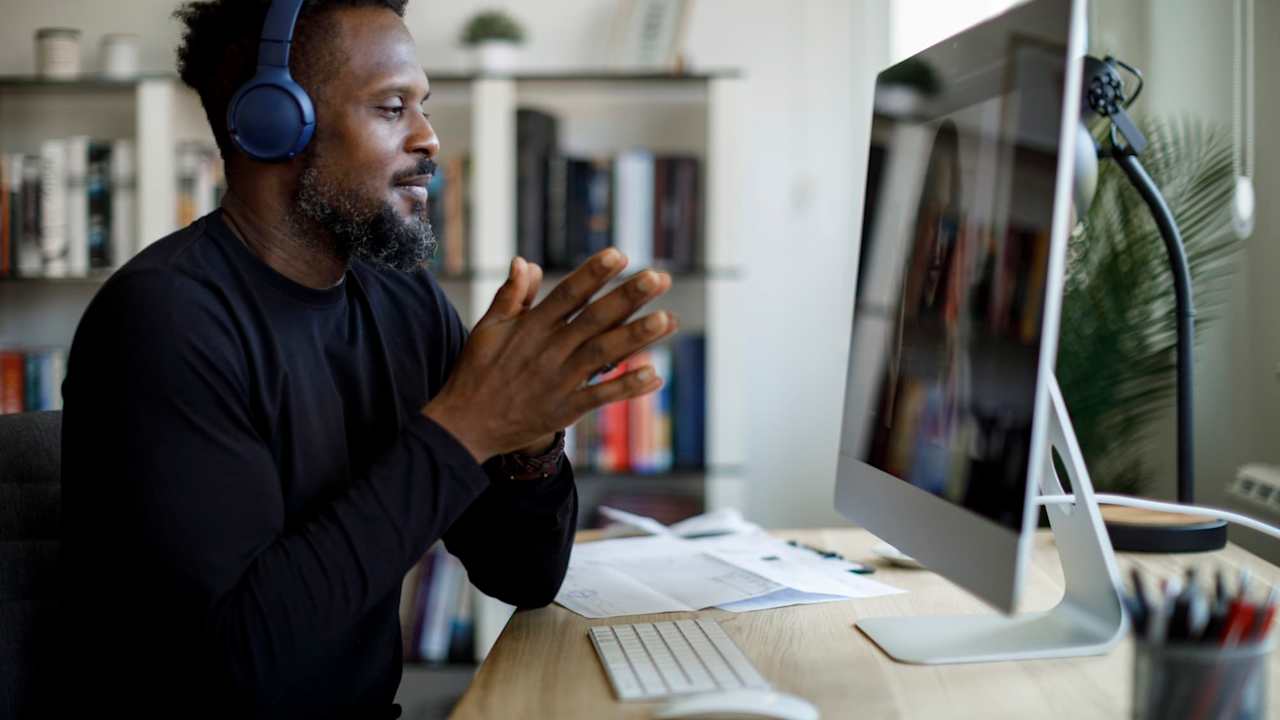 Smiling man with headphones having video call at home office