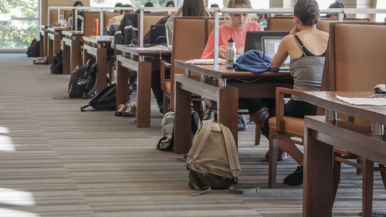 View down the sunny aisle of the Albert Hutzler Reading Room, a two-story silent reading room in the Brody Learning Commons of Johns Hopkins University; college students work at rows of tables with laptops and backpacks all around them; Baltimore, Maryland, March, 2014. Courtesy Eric Chen. (Photo by JHU Sheridan Libraries/Gado/Getty Images).