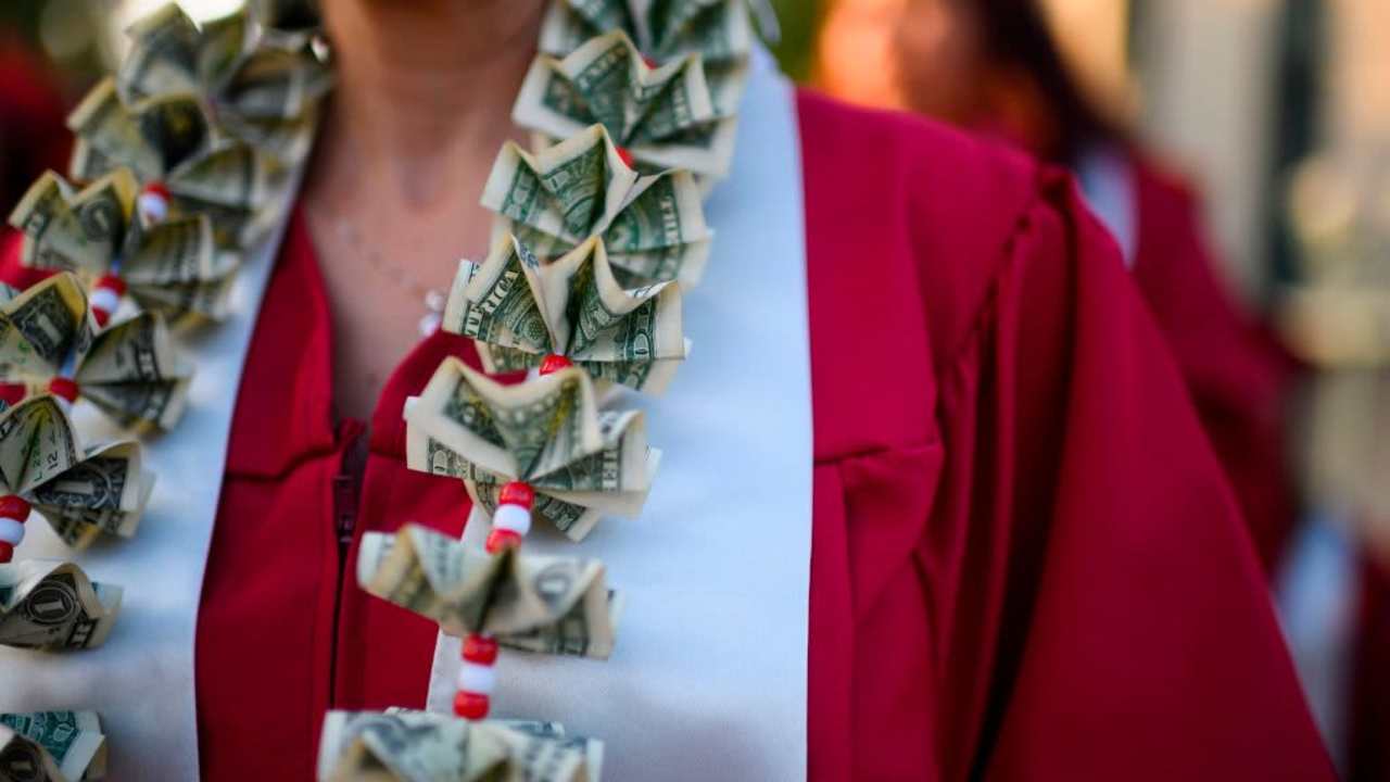A graduating student wears a money lei, a necklace made of US dollar bills, at the Pasadena City College graduation ceremony, June 14, 2019, in Pasadena, California. - With 45 million borrowers owing $1.5 trillion, the student debt crisis in the United States has exploded in recent years and has become a key electoral issue in the run-up to the 2020 presidential elections. "Somebody who graduates from a public university this year is expected to have over $35,000 in student loan debt on average," said Cody Hounanian, program director of Student Debt Crisis, a California NGO that assists students and is fighting for reforms. (Photo by Robyn Beck / AFP) (Photo credit should read ROBYN BECK/AFP via Getty Images)