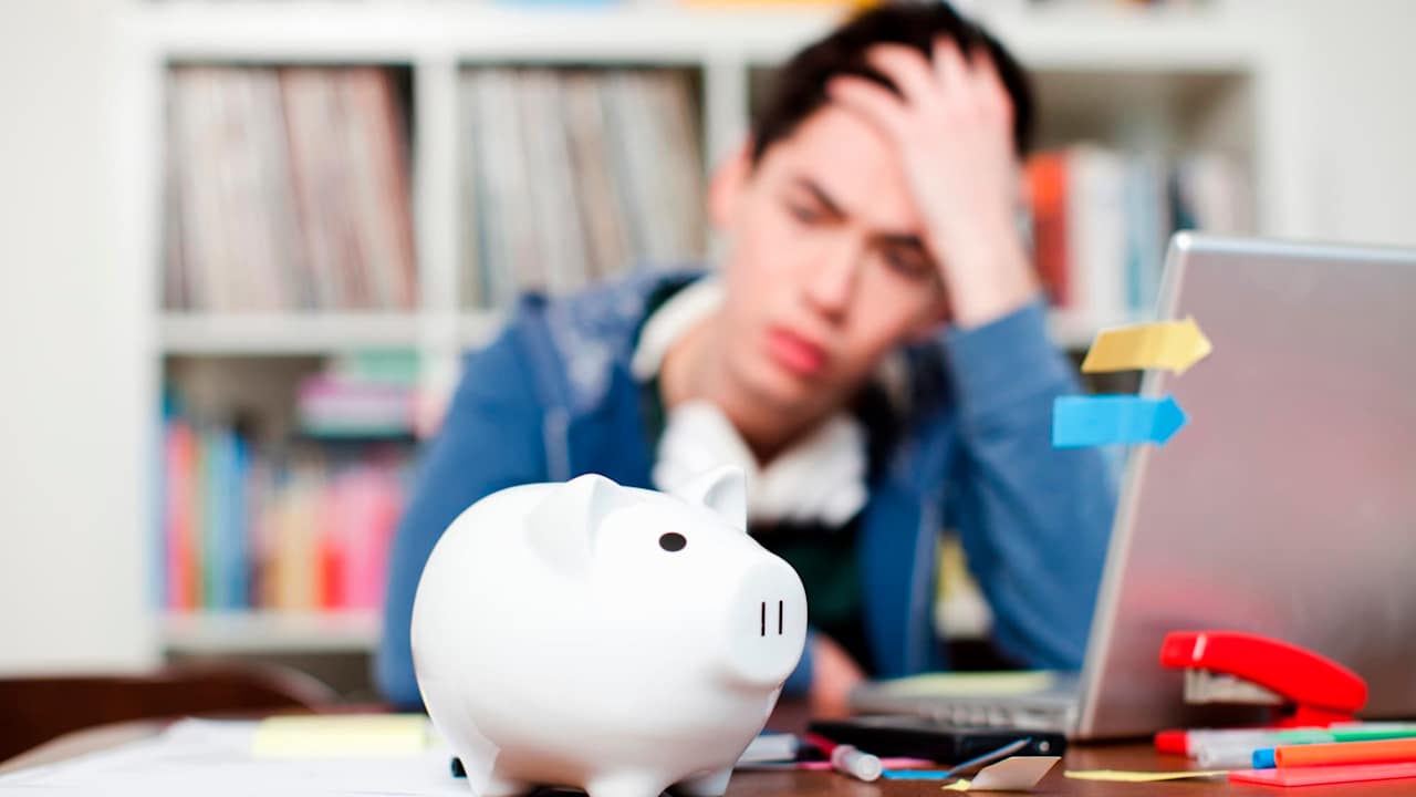 Piggy bank with young man worrying in background