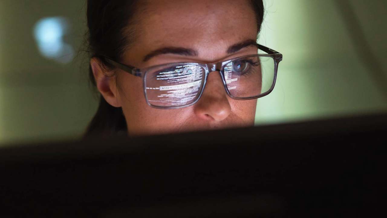 Close-up of a female computer programmer writing code on her desktop computer at work.