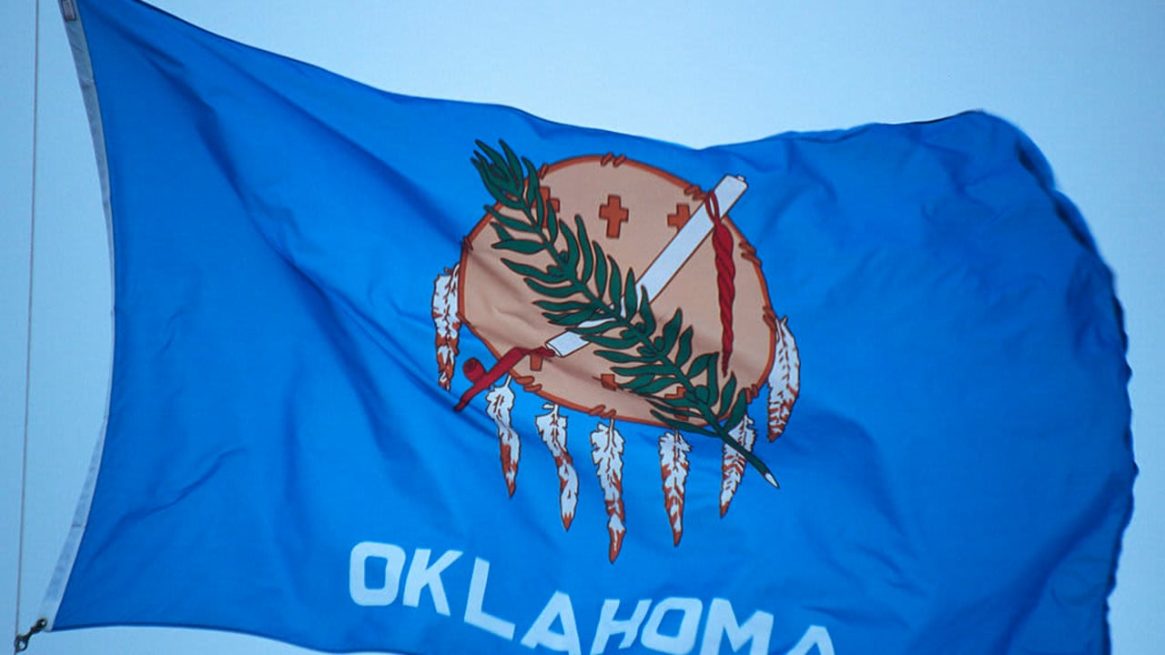 The state flag of Oklahoma flying in the wind on a sunny day.