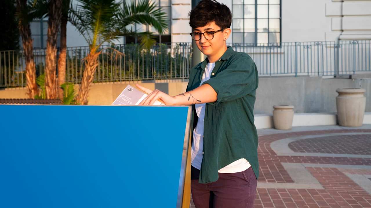 Female college student drops off her absentee ballot into the Official Ballot Drop Box in front of City Hall in Pasadena, California.