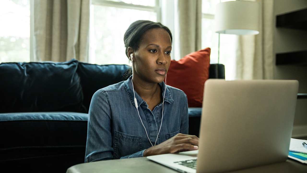 Woman working on a laptop wearing headphones