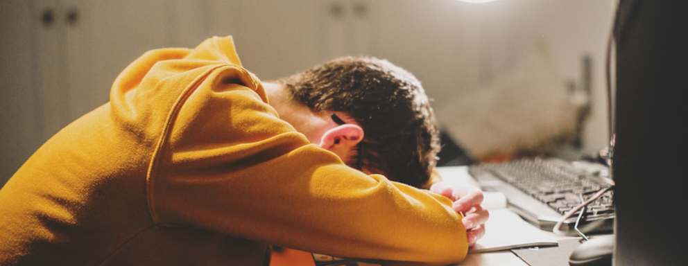 A stressed student laying there head down on their desk while working late at night