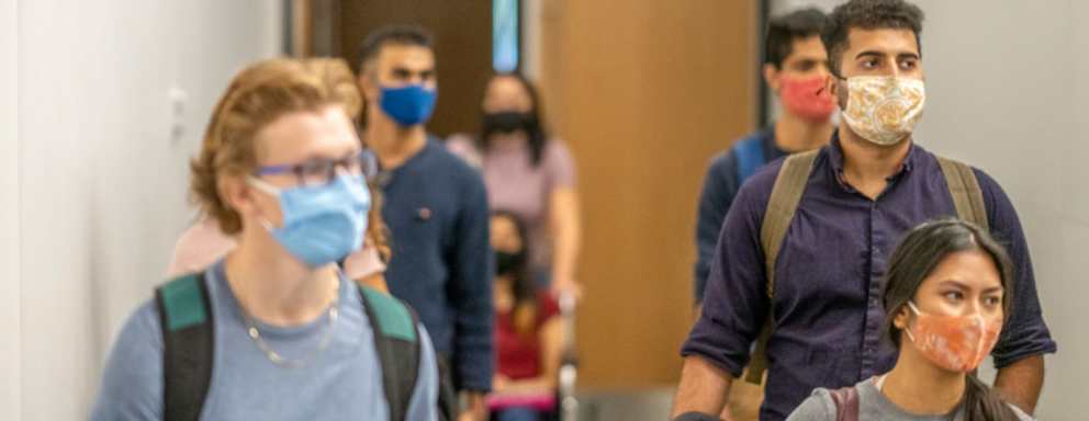 Colleges students filing into class while wearing protective face masks.