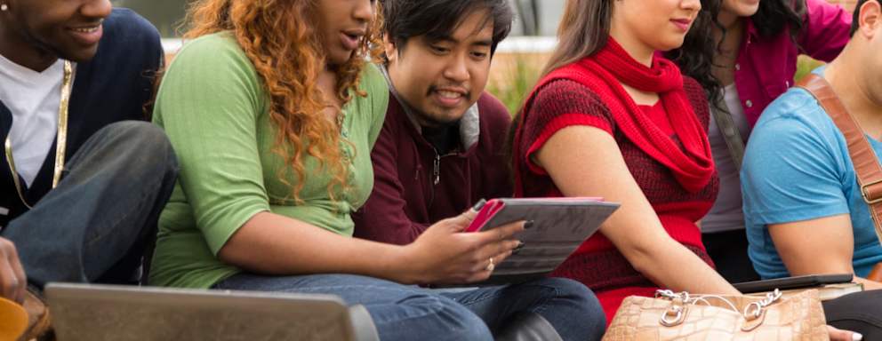 Group of multi-ethnic international college students hanging together outside on a campus square.