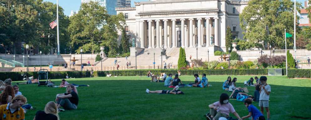 People sit on the grass at Columbia University in New York City. The university said it needs more time to reevaluate its data after a professor alleged it may have skewed numbers in previous years.