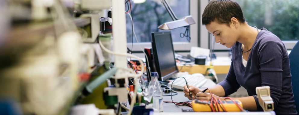Community college technician student fixing an electronic device in a workshop on campus.