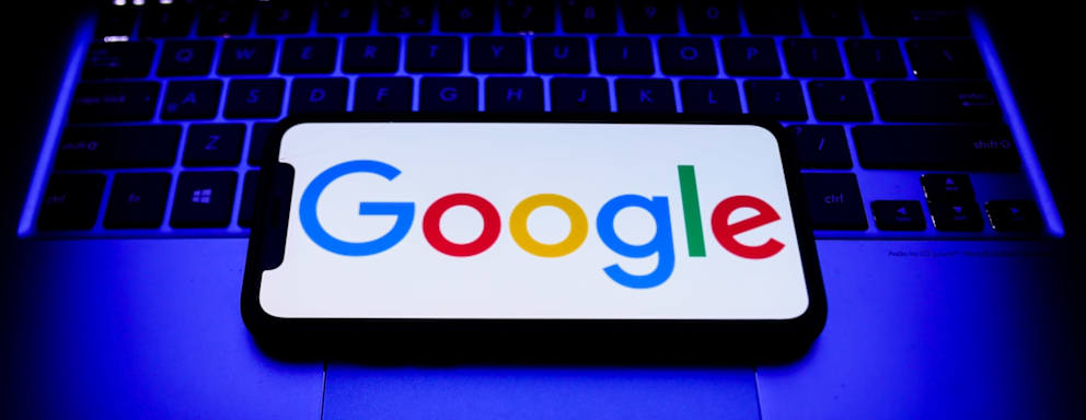 Google logo displayed on a phone screen and a laptop keyboard are seen in this illustration photo