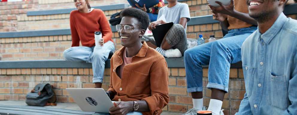 Smiling young multi-ethnic students enjoying while sitting on amphitheater at university campus
