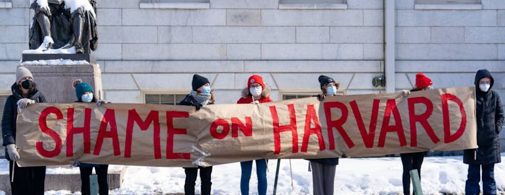 Demonstrators hold a banner during a 'No Justice Walkout' protest at Harvard University in Cambridge, Massachusetts, U.S., on Monday, Feb. 14, 2022. Harvard allowed a star professors sexual abuse of female students to continue unchecked for decades, contributing to a culture of harassment in its Anthropology Department, a new lawsuit alleges. Harvard University disputes the allegations of the lawsuit.