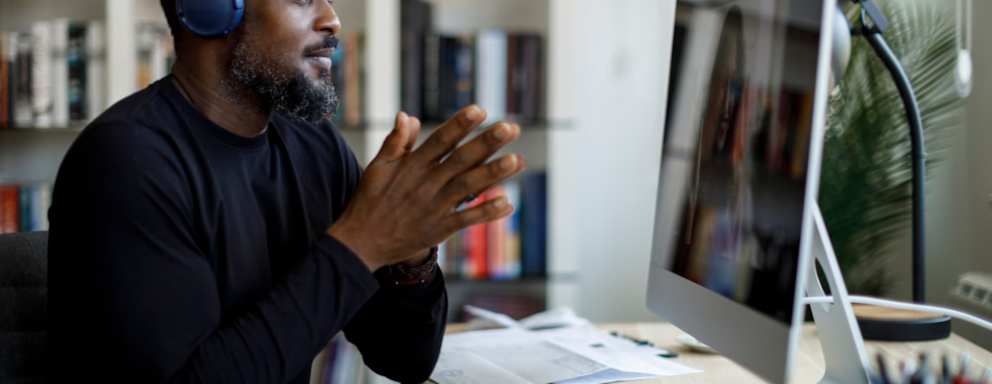 Smiling man with headphones having video call at home office