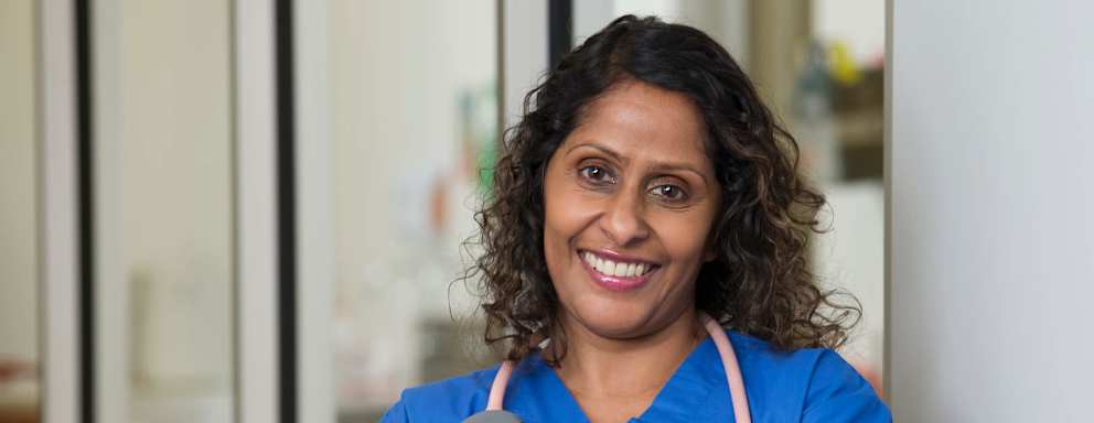 Female Indian-American nurse smiling while standing in a hospital lobby