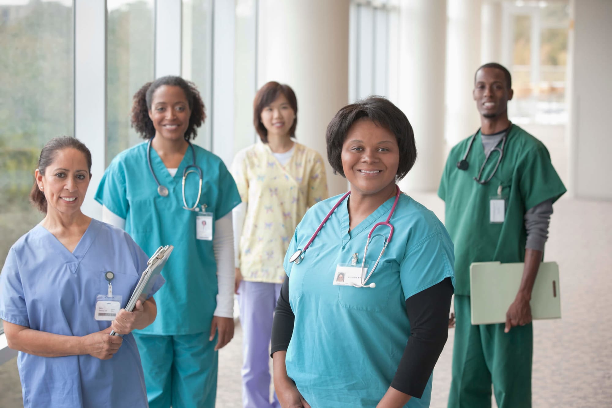 A diverse group of five male and female nurses standing in a hospital hallway