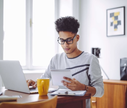 Young Black male college student working on his laptop at home