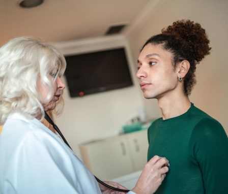 Nurse listening to a transgender patient's heartbeat in a hospital room