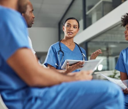 Nurses sitting and talking to one another about the course of treatment for their patients