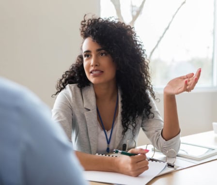 Young adult female public health professional discusses her notes during a meeting with a colleague.