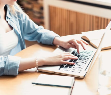 Woman at home typing her resume on her laptop.