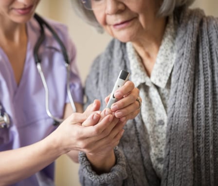 Nurse giving blood sugar test to patient in home