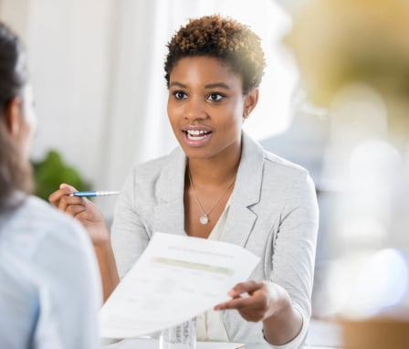 A young black woman presenting a copy of her resume during an interview.