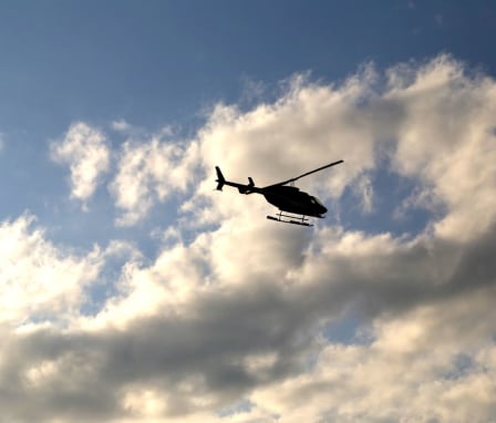 Silhouette of a medical helicopter flying in the partially cloudy sky