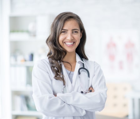 Medical professional in white coat smiling in an exam room