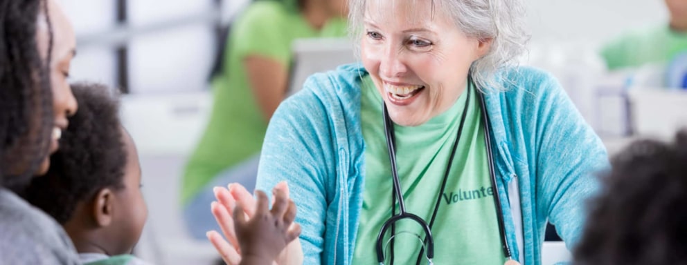 Senior woman medical volunteer smiles at baby
